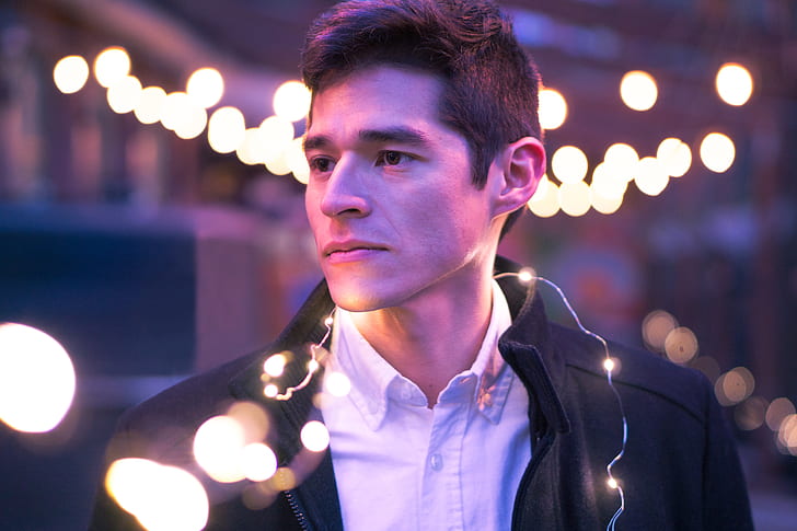 man in white collared shirt with black jacket with string lights