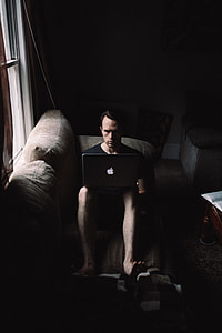 photo of man sitting with MacBook